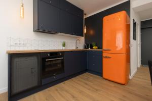 an orange refrigerator in a kitchen with black cabinets at Stylish Apartment Warsaw Downtown by Renters in Warsaw