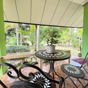 une terrasse avec une table et des chaises ainsi qu'une grande fenêtre. dans l'établissement Happy Resort, à Khanom