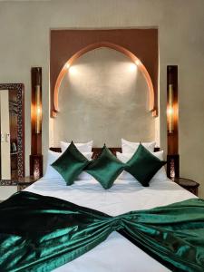 a bedroom with a large bed with green pillows at Riad Dar Zaouia in Marrakech