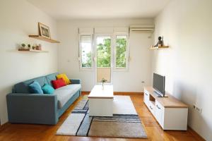 uma sala de estar com um sofá azul e uma televisão em Apartment GOLD em Podgorica