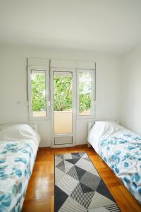 duas camas num quarto com duas janelas e um tapete em Apartment GOLD em Podgorica