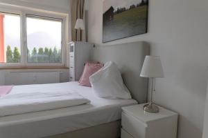 1 dormitorio con cama blanca y ventana en Ferienwohnungen BergArt, en Iselsberg