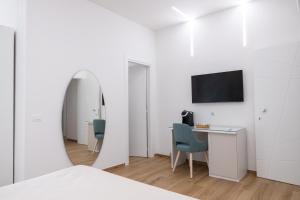 a white bedroom with a desk and a tv at Sunbay Luxury Rooms in Vieste