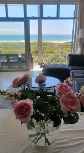 a vase filled with pink roses on a table at Beachfront 3-bedroom with Robben Island views in Cape Town