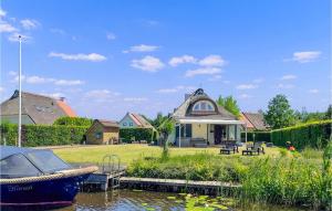 una casa con un barco en el agua frente a ella en Nice Home In Sint Nicolaasga With House Sea View, en Sint Nicolaasga