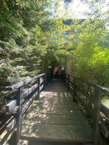 een houten loopbrug in een park met bomen bij Hotel Amigo II in Kobuleti