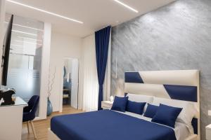 Un dormitorio con una cama azul y blanca y un escritorio en Sunbay Luxury Rooms, en Vieste