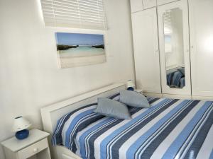 a bedroom with a bed with blue and white stripes at KASPOZ Entire Holiday Home - Private garden & 5 mins walk to the beach in Mont Choisy