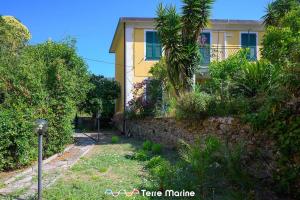 een geel huis met een stenen muur en bomen bij Nettuno, TerreMarine in Monterosso al Mare