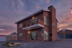 a brick house with a sunset in the background at Land's Edge Eco Friendly Cottages and Apartments in Struisbaai