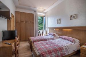 a bedroom with two beds and a flat screen tv at Hotel Pinzolo-Dolomiti in Pinzolo