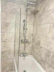 um chuveiro com uma banheira branca na casa de banho em Lovely 4 Bedroom House with 2 Bathroom, Garden and Private Parking em Thornton Heath