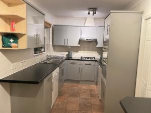 a kitchen with white cabinets and a black counter top at Lovely 4 Bedroom House with 2 Bathroom, Garden and Private Parking in Thornton Heath