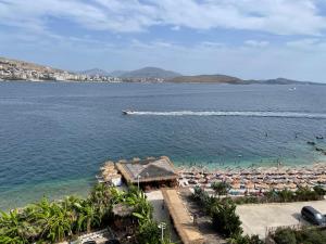 a beach with umbrellas and a boat in the water at Port Side Sarande in Sarandë