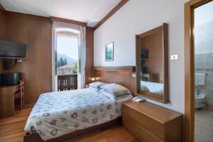 um quarto com uma cama e um espelho grande em Hotel Pinzolo-Dolomiti em Pinzolo