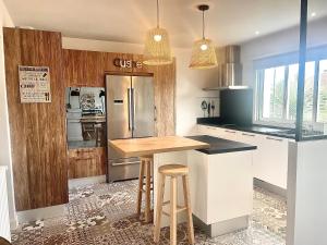a kitchen with a counter with a refrigerator and stools at Villa Nolaene, 8-9 pers, Piscine, Calme et Moderne in Gujan-Mestras