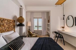 Un dormitorio con una cama y un escritorio y sillas. en Arotron Santorini, en Pirgos