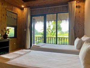 a bedroom with a bed and a large window at Mường Village Ninh Bình in Ninh Binh