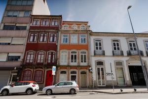 twee auto's geparkeerd voor gebouwen in een straat bij Theater Studio in Porto