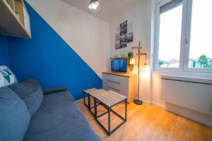 a living room with a couch and a blue wall at Le Moka II et sa terrasse Cosy in Fontaine