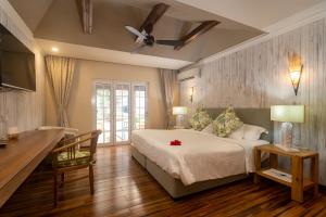 a bedroom with a bed and a table and a desk at Felicie Cottage & Residence in Anse Royale