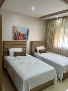 een slaapkamer met 2 bedden en een schilderij aan de muur bij Immeuble Familial Imad in Tetouan
