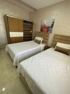 two beds in a hotel room with two bedsvisor at Immeuble Familial Imad in Tétouan