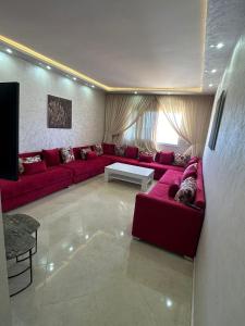 een woonkamer met een rode bank en een tafel bij Immeuble Familial Imad in Tetouan