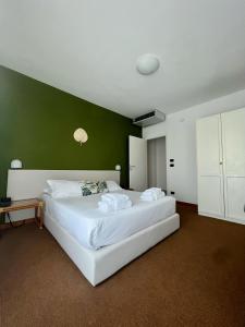リド・ディ・イエゾロにあるHarvey Suites Hotel & Residenceの緑の壁のベッドルーム1室(白いベッド1台付)