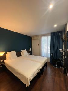 - une chambre avec un grand lit blanc et un mur bleu dans l'établissement B&B HOTEL Perpignan Centre, à Perpignan