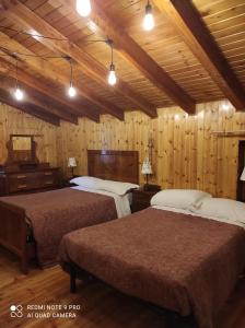 two beds in a room with wooden walls at Baita "la Brenva" Pialemont Champorcher - CIR VDA - PONTBOSET 0001 in Pontboset