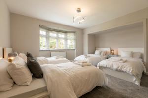 ein weißes Schlafzimmer mit 2 Betten und einem Fenster in der Unterkunft Home in Saltford with Hot Tub and Sauna. in Saltford