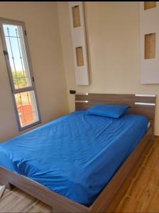 a bedroom with a blue bed with a window at Jawharat marrakech in Marrakech