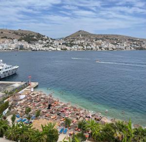 a beach with umbrellas and people in the water at Port Side Sarande in Sarandë