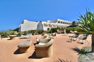um pátio com cadeiras e mesas e um edifício em Cossyra Hotel em Pantelleria