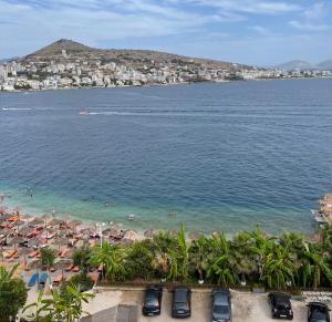 a beach with umbrellas and people in the water at Port Side Sarande in Sarandë