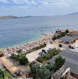 a beach with umbrellas and people in the water at Port Side Sarande in Sarandë