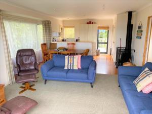 a living room with a blue couch and a chair at Aqua Views - Kuratau Holiday Home in Kuratau