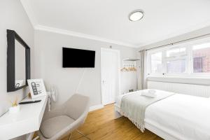 ein weißes Schlafzimmer mit einem Bett und einem Stuhl in der Unterkunft Rose Terrace in London