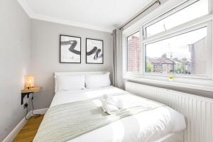 a white bedroom with a bed and a window at Rose Terrace in London