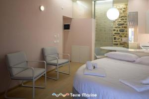 a bedroom with a bed and two chairs and a kitchen at Sea-Cret, TerreMarine in Manarola