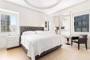 a white bedroom with a large bed and a chair at Luxury Midtown West 4 Bedroom Apartment Near Radio City in New York