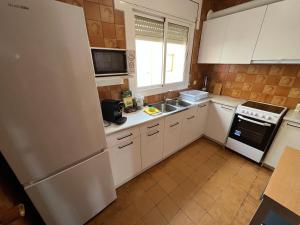 une cuisine avec des armoires blanches et un réfrigérateur dans l'établissement El Llobarret de Baix a Mar, à Torredembarra