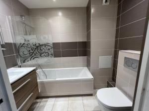ein Badezimmer mit einer Badewanne, einem WC und einem Waschbecken in der Unterkunft Spacious & modern flat close to Parc Monceau in Paris