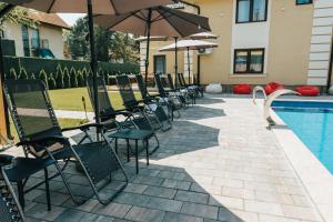 una fila de sillas y sombrillas junto a una piscina en HOTEL Villa Cvijanović - WELLNESS-SPA en Palić