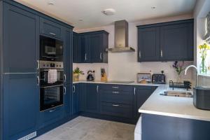 a kitchen with blue cabinets and a sink at Fleming Cottage - Contemporary Cotswold Home 