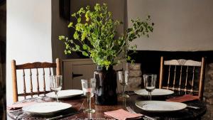 a table with plates and a vase with flowers on it at Armada Cottage in Charlbury