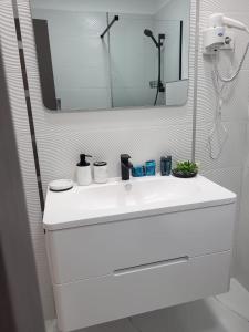 a bathroom with a white sink and a mirror at Savoy Mamaia Studio in Mamaia