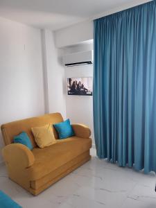 a couch in a living room with blue curtains at Savoy Mamaia Studio in Mamaia