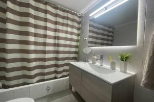 a bathroom with a sink and a shower curtain at Serenity apartment in Pýrgos